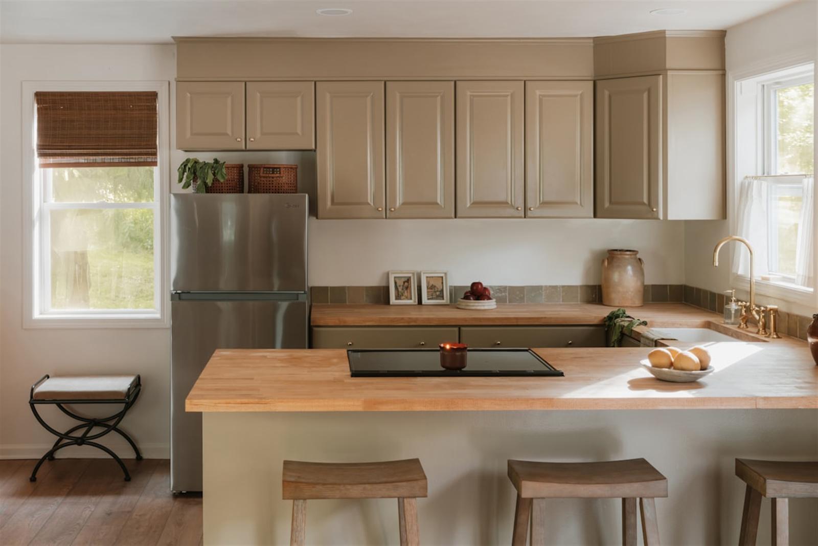 Bright farmhouse kitchen featuring a light wood butcher-block-style countertop and island