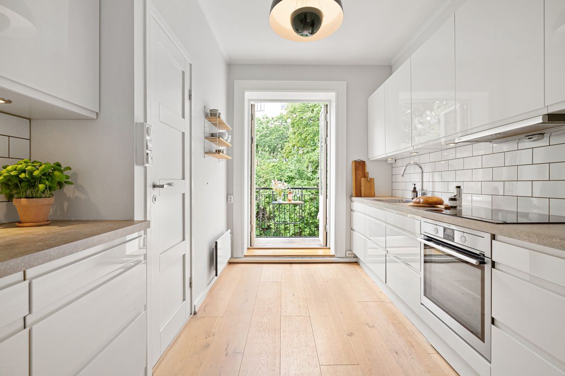 A modern white kitchen with handleless flat panel slab cabinet doors and a minimalist island