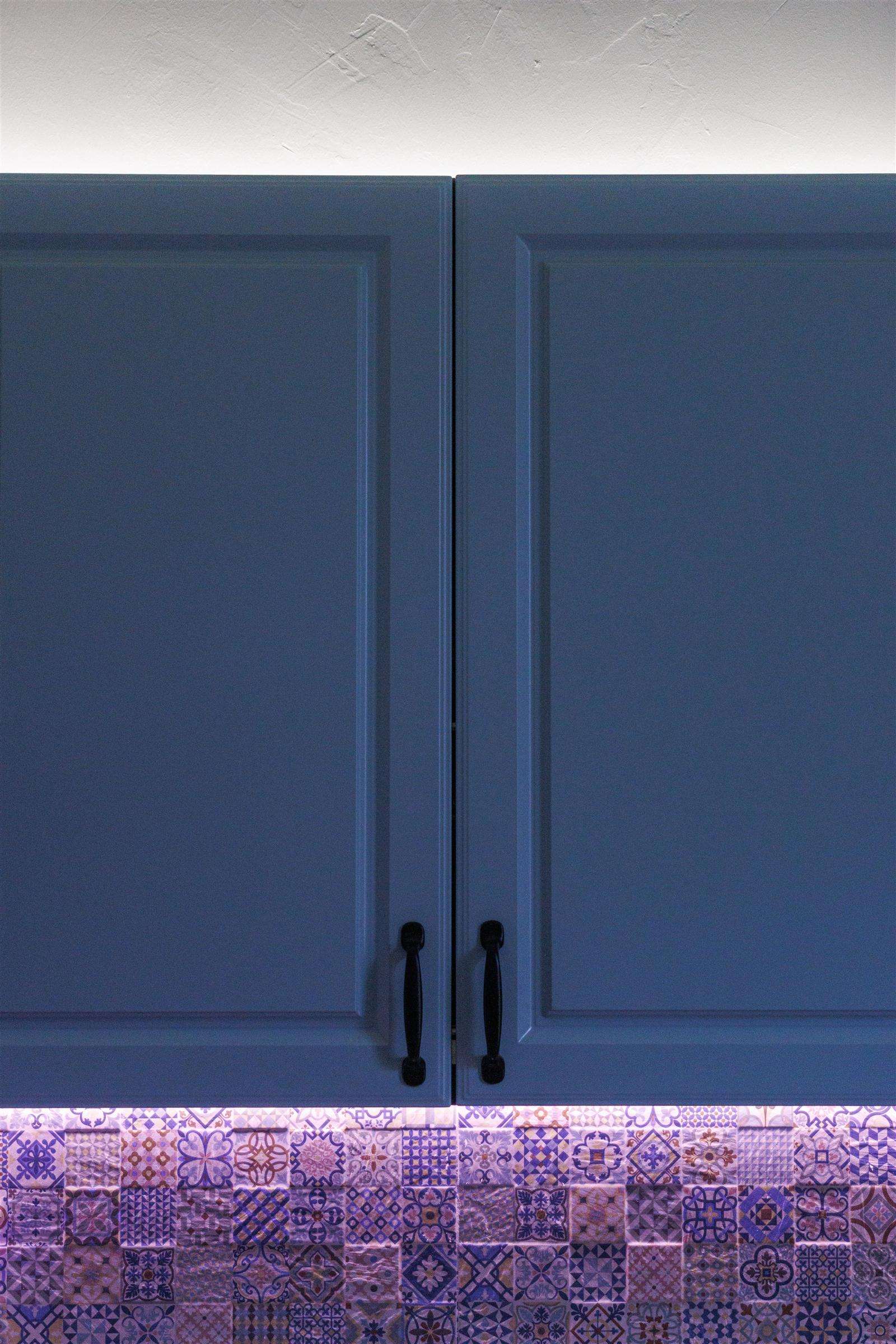 Modern blue kitchen cabinets with decorative patterned tile backsplash and under-cabinet lighting
