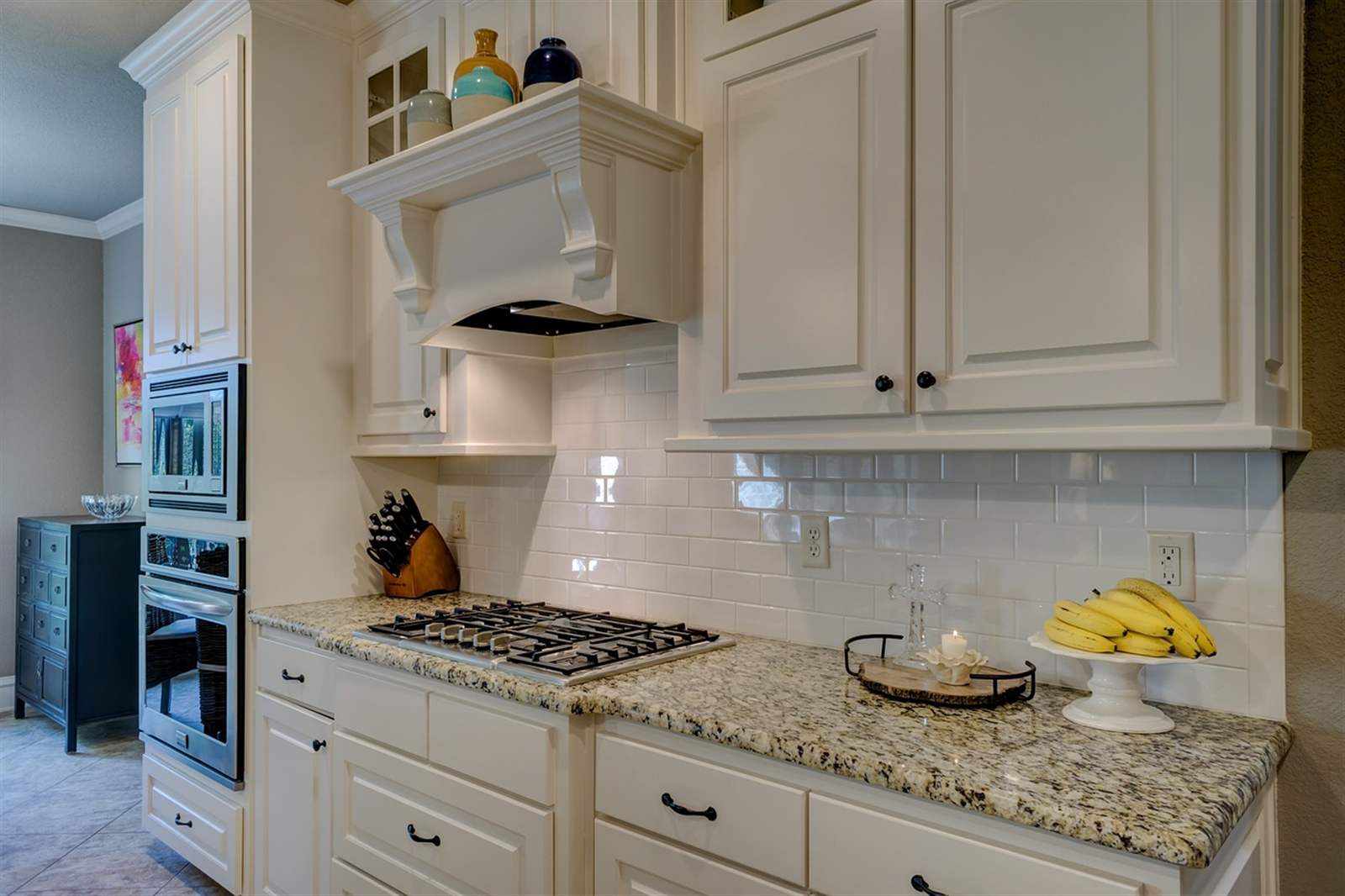 Light-filled galley kitchen with white cabinetry and hardwood floors, staged for a home sale