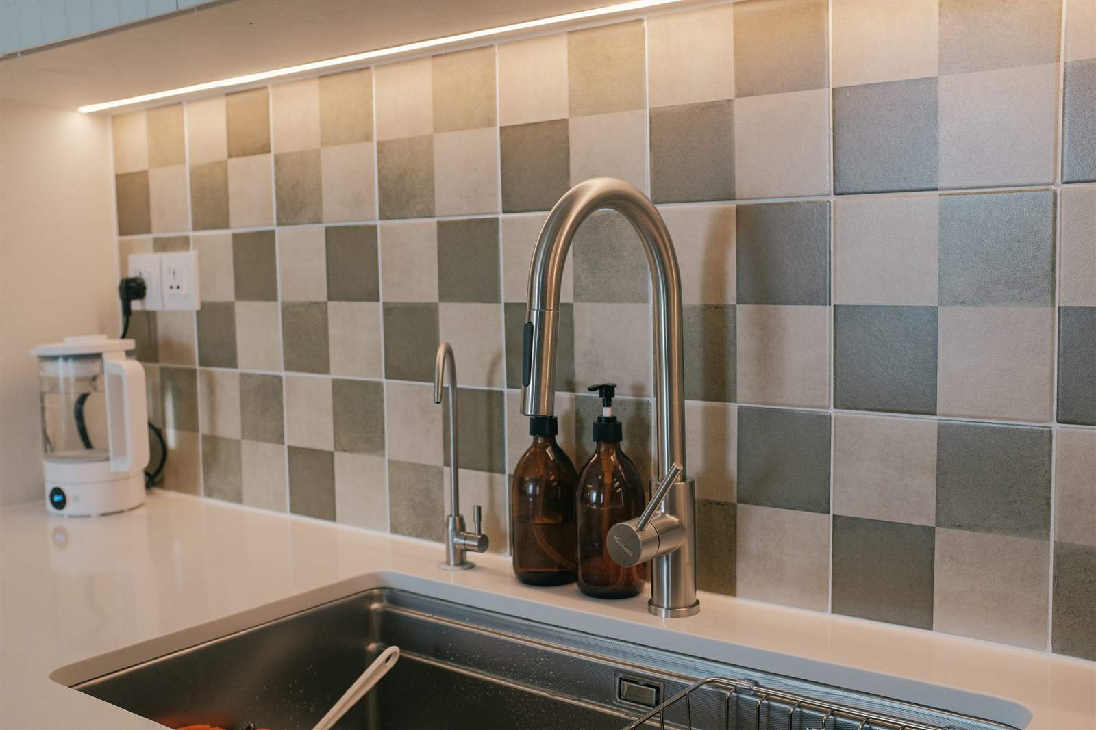 Close-up of a stainless steel kitchen sink basin with faucet and soap dispenser installed